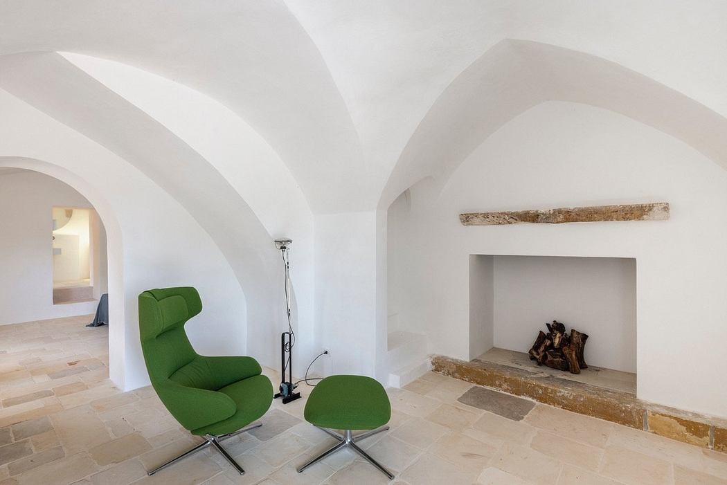 Bright, minimalist interior with arched ceilings, green lounge chair, and fireplace.