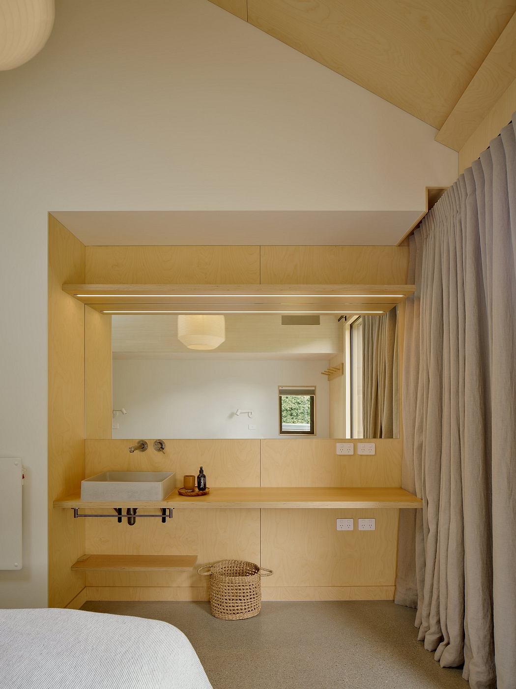 A modern bedroom with sleek wooden built-in storage and a minimalist vanity area.