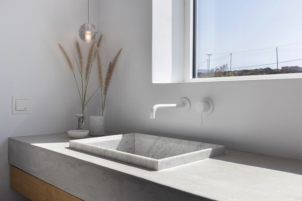 Minimalist bathroom design with marble vanity, wall-mounted faucet, and spherical pendant light.
