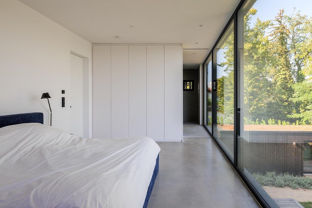 Modern bedroom with floor-to-ceiling windows, built-in closets, and concrete floors.