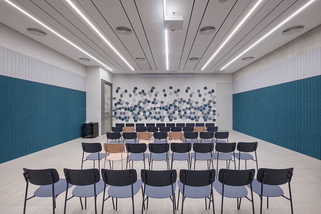 Modern conference room with sleek lighting, hexagonal wall pattern, and rows of chairs.
