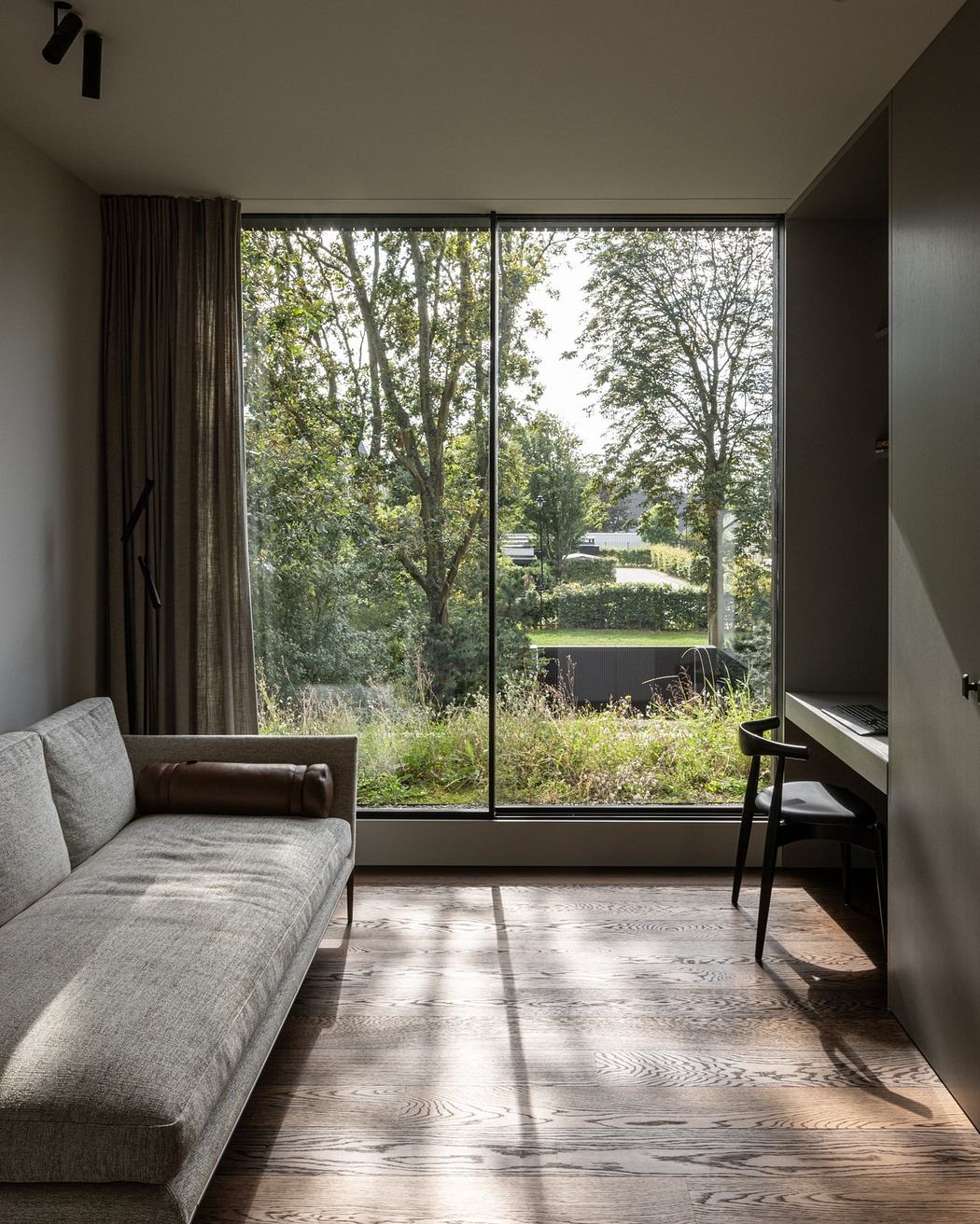 A cozy living space with floor-to-ceiling windows framing a lush, verdant landscape.