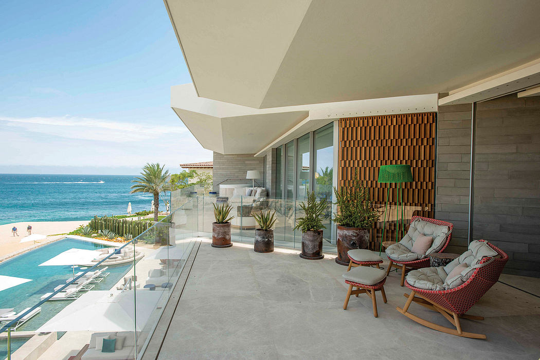 Striking modern beachfront terrace with sleek glass walls, plush seating, and tropical accents.