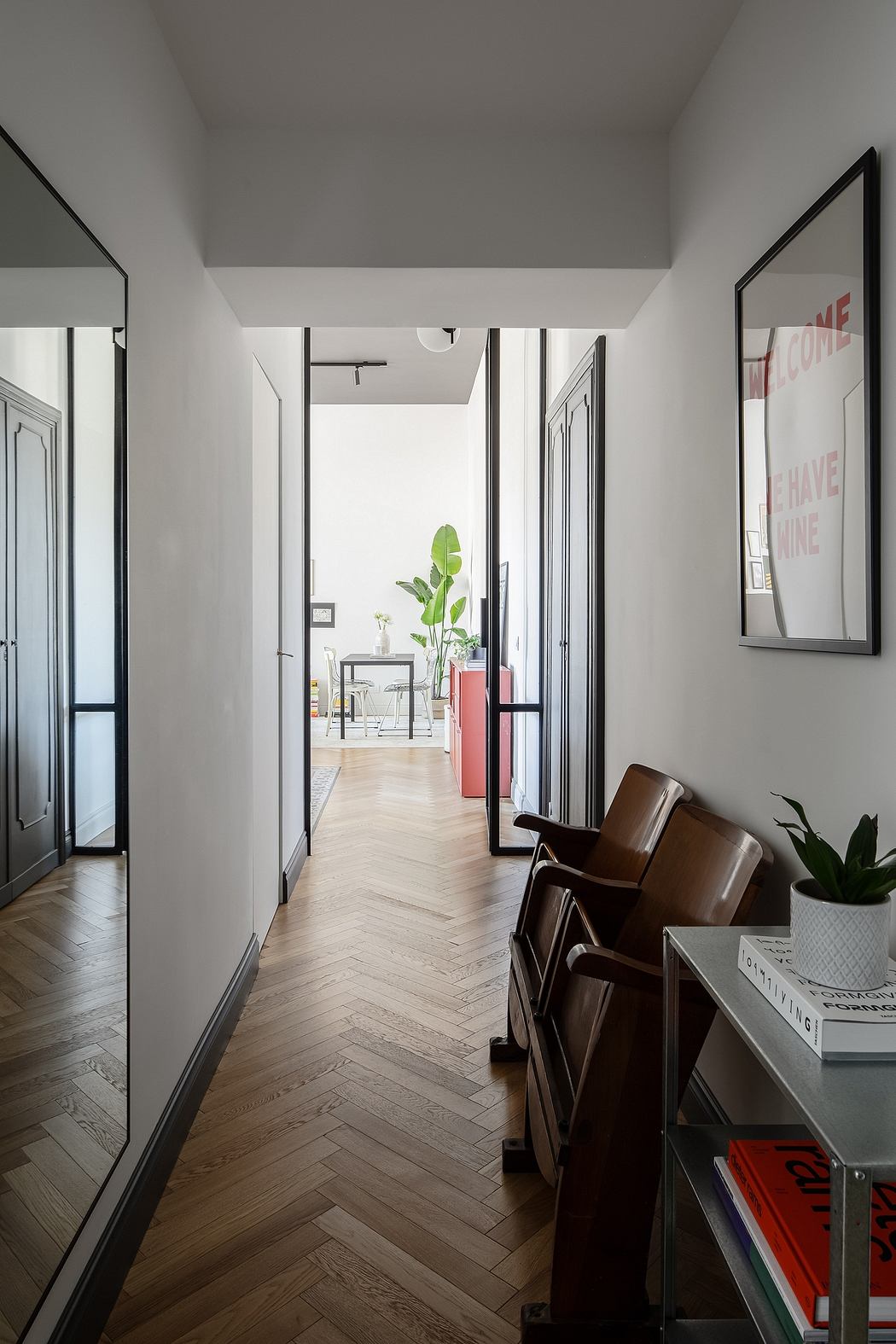 Bright, modern hallway with black-framed doors, herringbone wood floors, and potted plant.