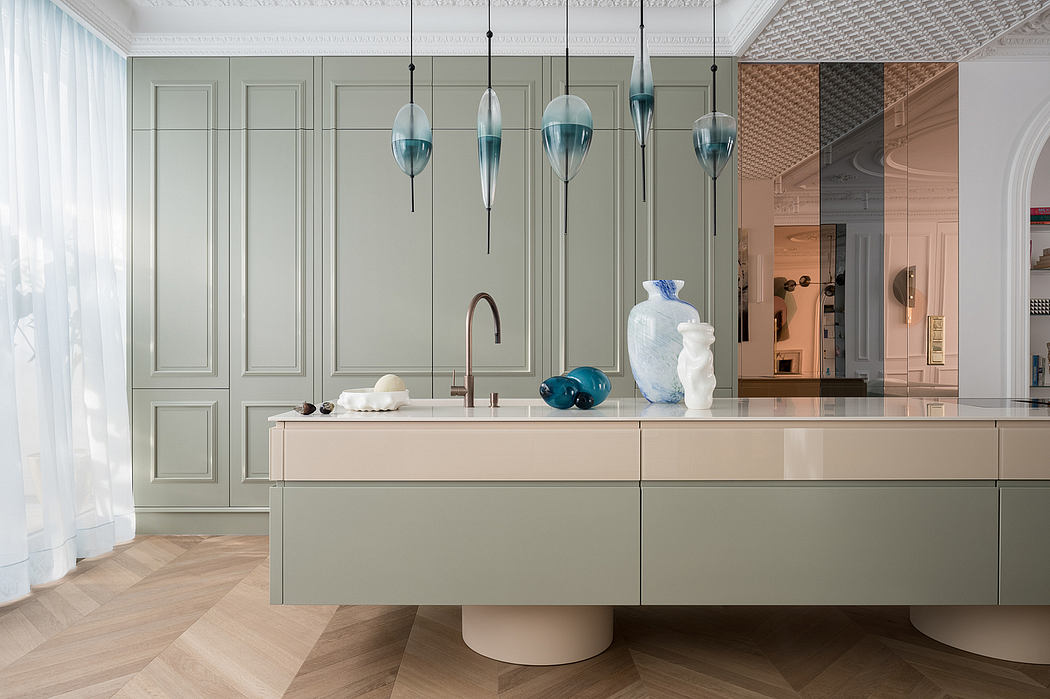 Elegant kitchen with sleek gray cabinetry, suspended glass pendant lights, and a sculptural island.