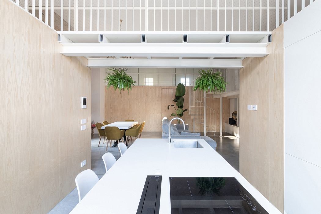 A modern, minimalist interior with a large white dining table, potted plants, and an open concept layout.