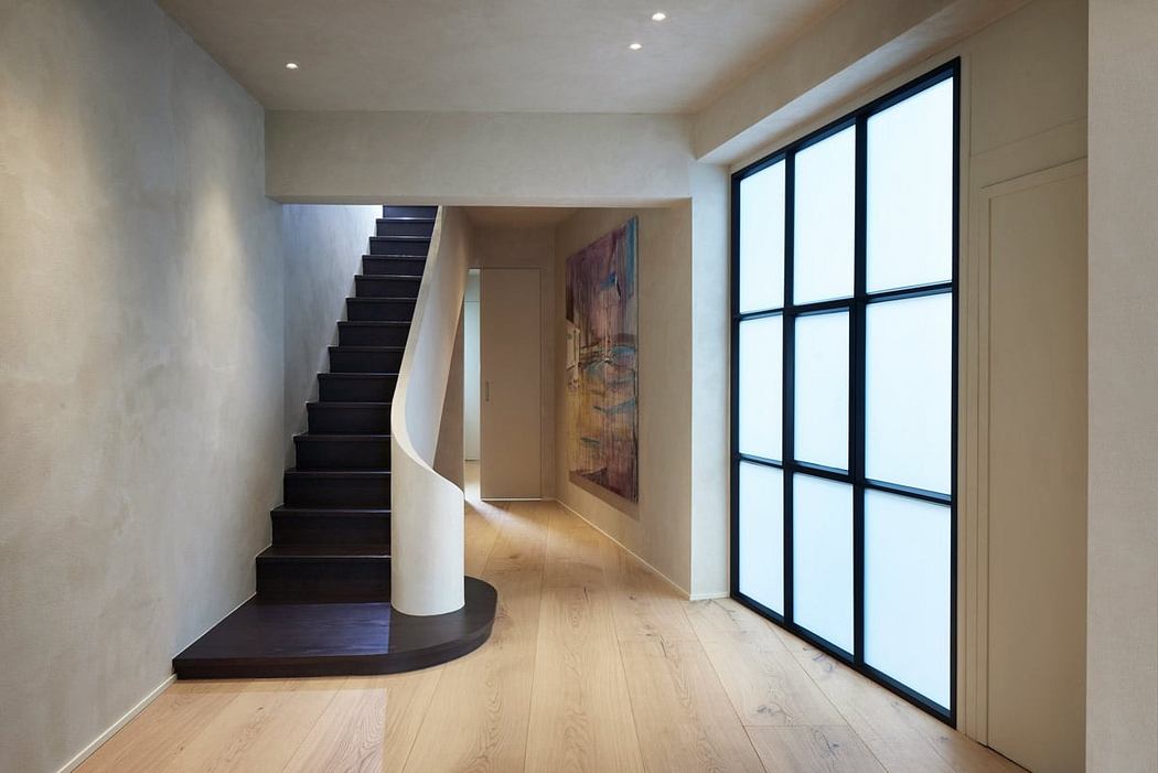Minimalist entryway with sleek black staircase, large windows, and modern artwork.