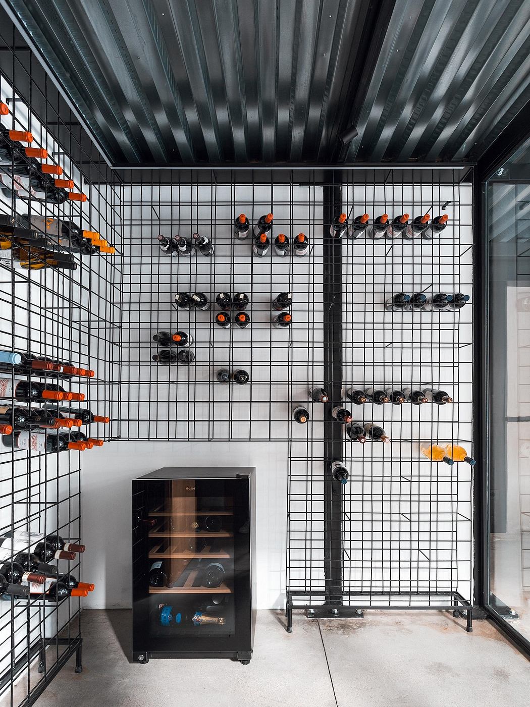 A black metal shelving unit displaying various wine bottles, with a beverage cooler below.