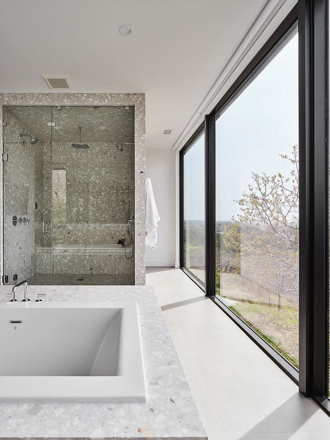 Serene modern bathroom with large window overlooking natural landscape.