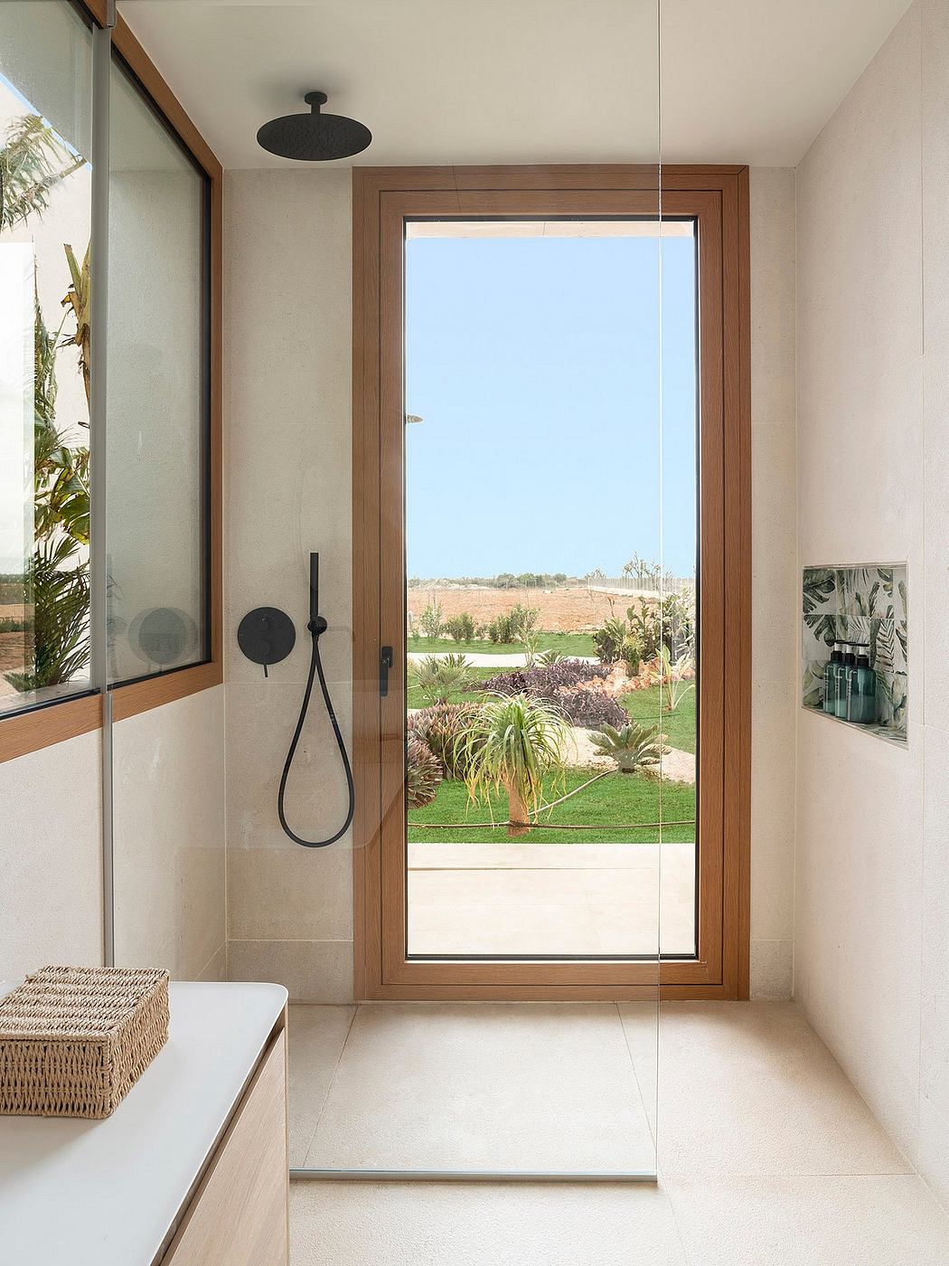 Modern bathroom with large window showcasing lush outdoor landscape. Sleek wood-framed design.