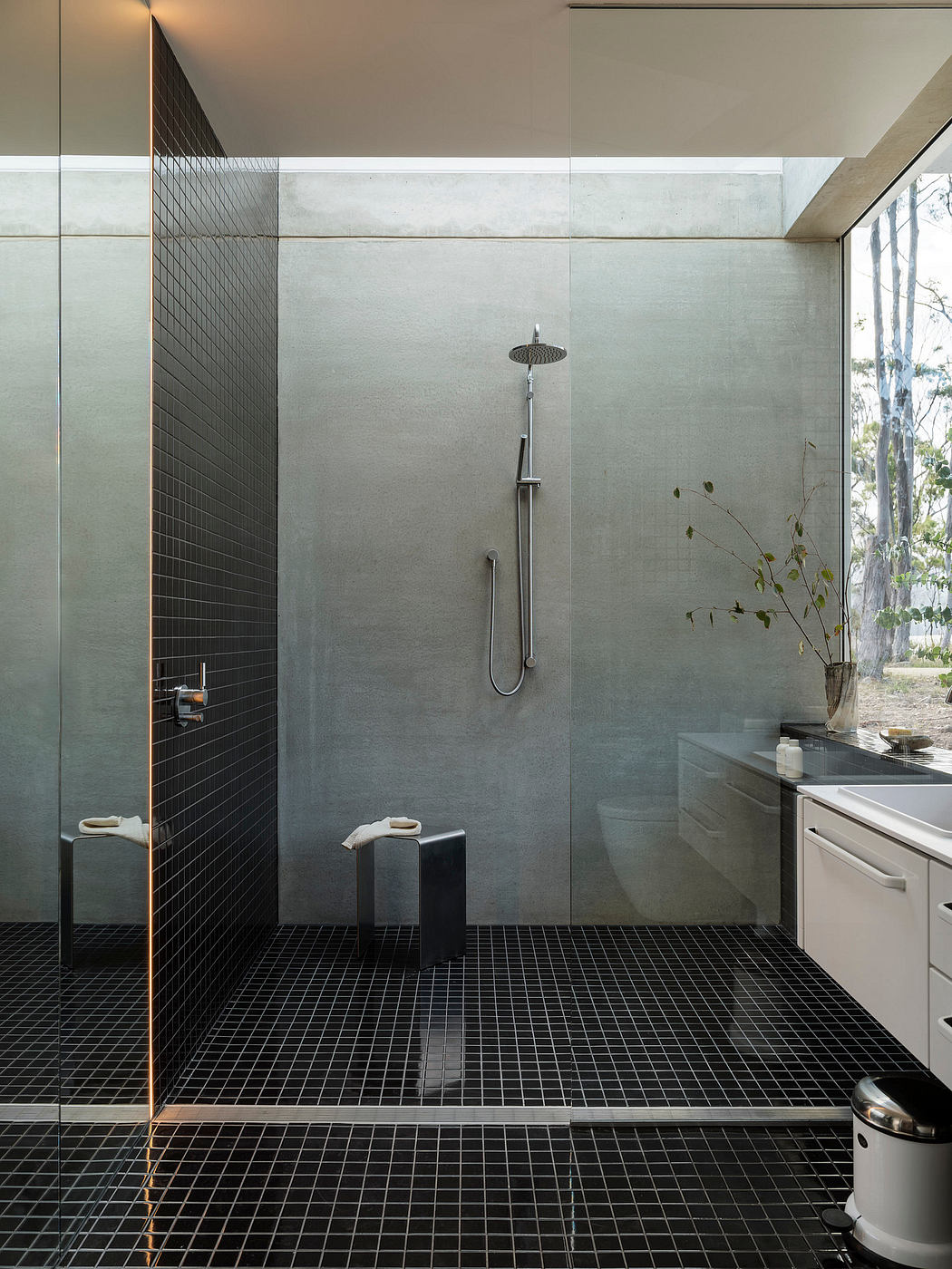 Sleek and modern shower area with black grid tiles and floor-to-ceiling glass panels.