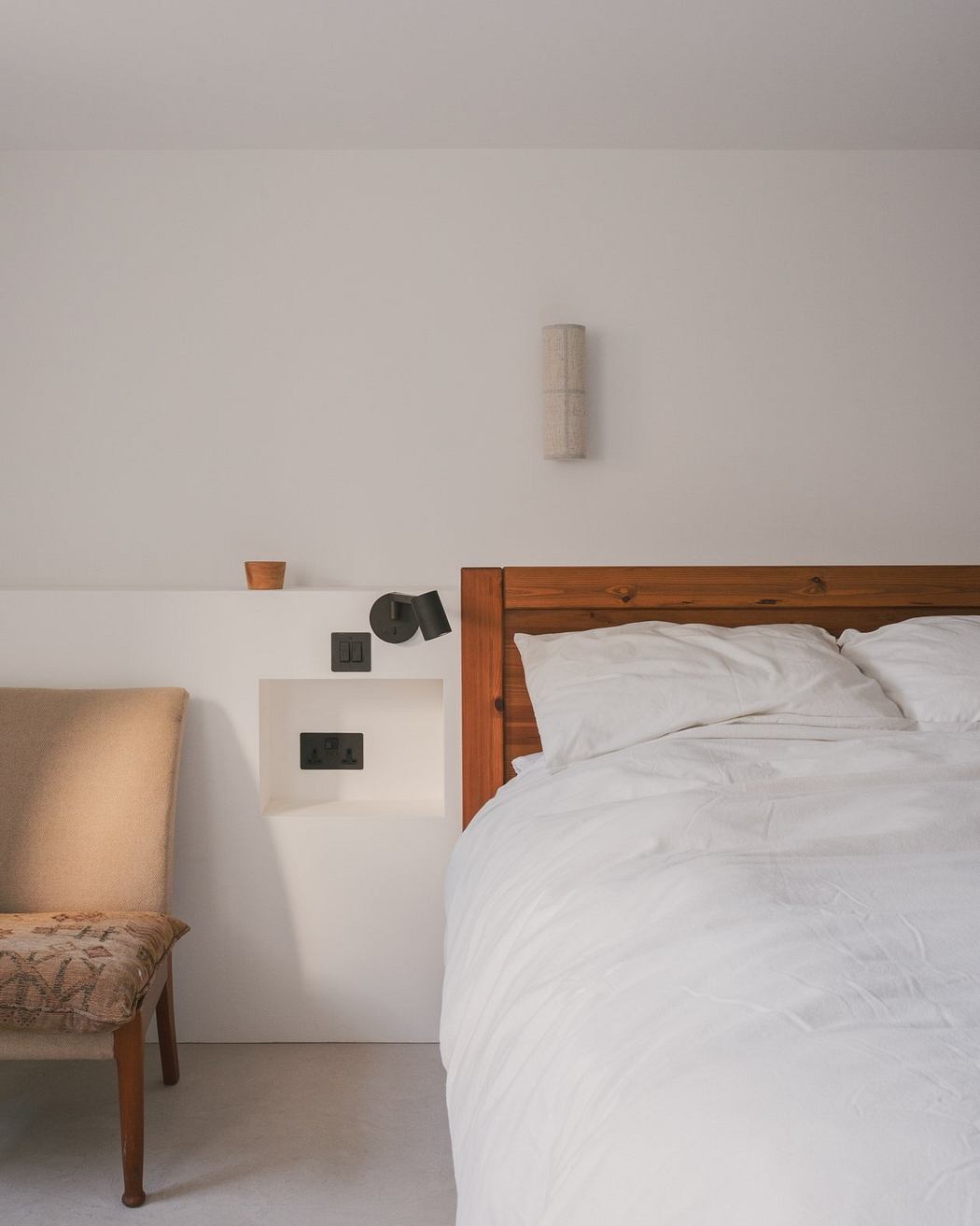 A cozy bedroom with a wooden bed frame, white bedding, and simple decor accents.