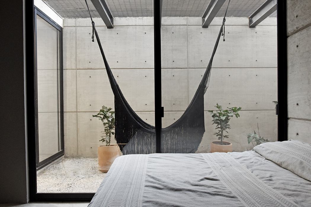 Minimalist concrete walls, hanging hammocks, and potted plants create a cozy, nature-inspired space.