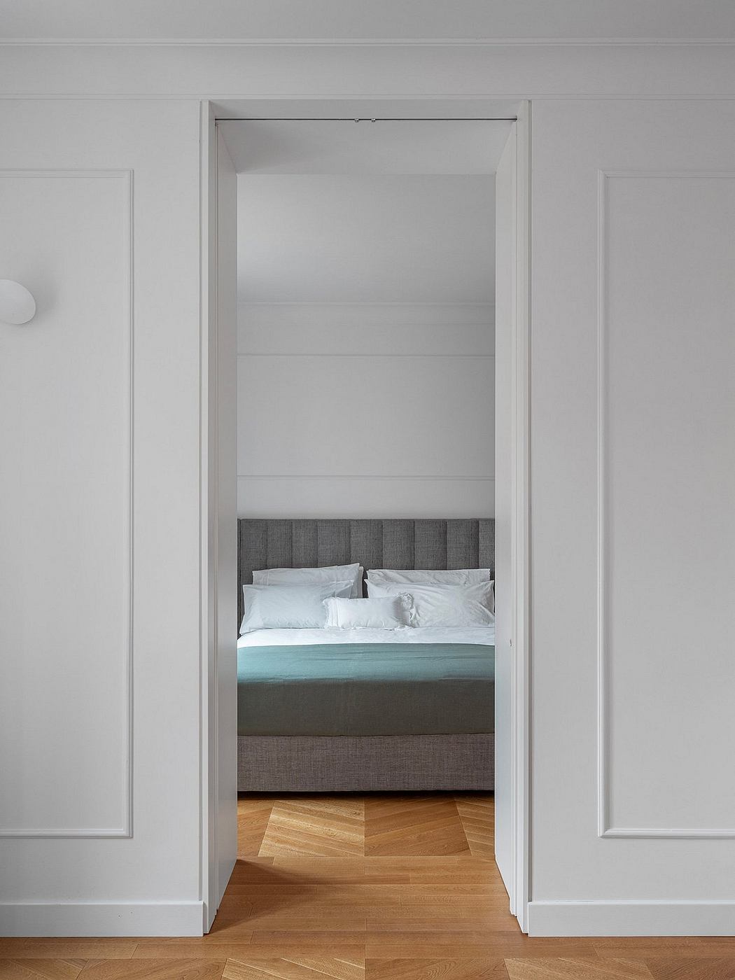 Minimalist bedroom design with clean lines, gray upholstered headboard, and hardwood floors.