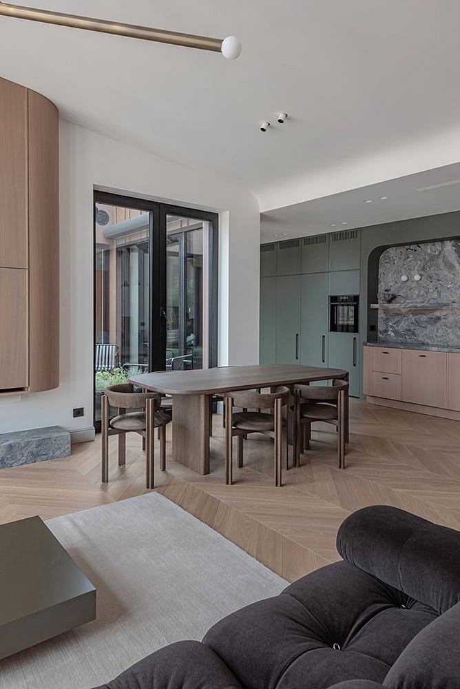Contemporary open-plan interior with wood-paneled walls, sleek dining furniture, and natural stone accent.