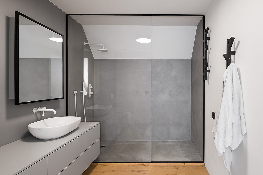 Modern, minimalist bathroom with concrete walls, vessel sink, and sleek black frame.