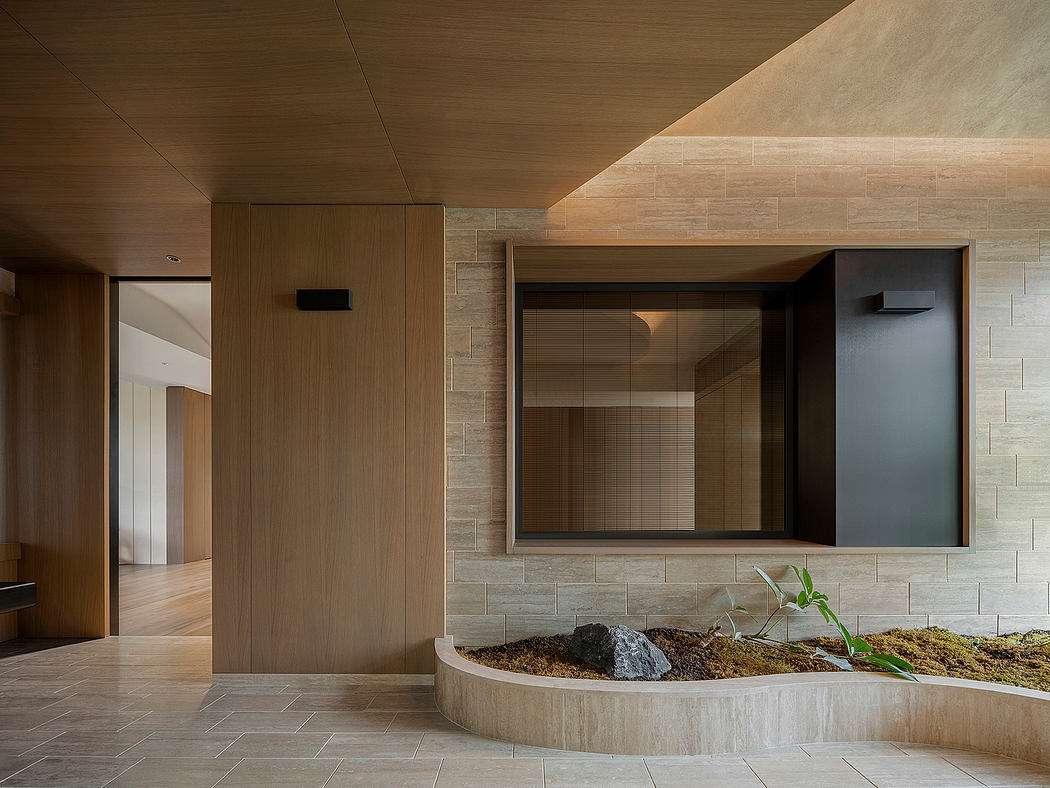 A minimalist entryway features wood paneling, stone tiles, and a built-in planter.