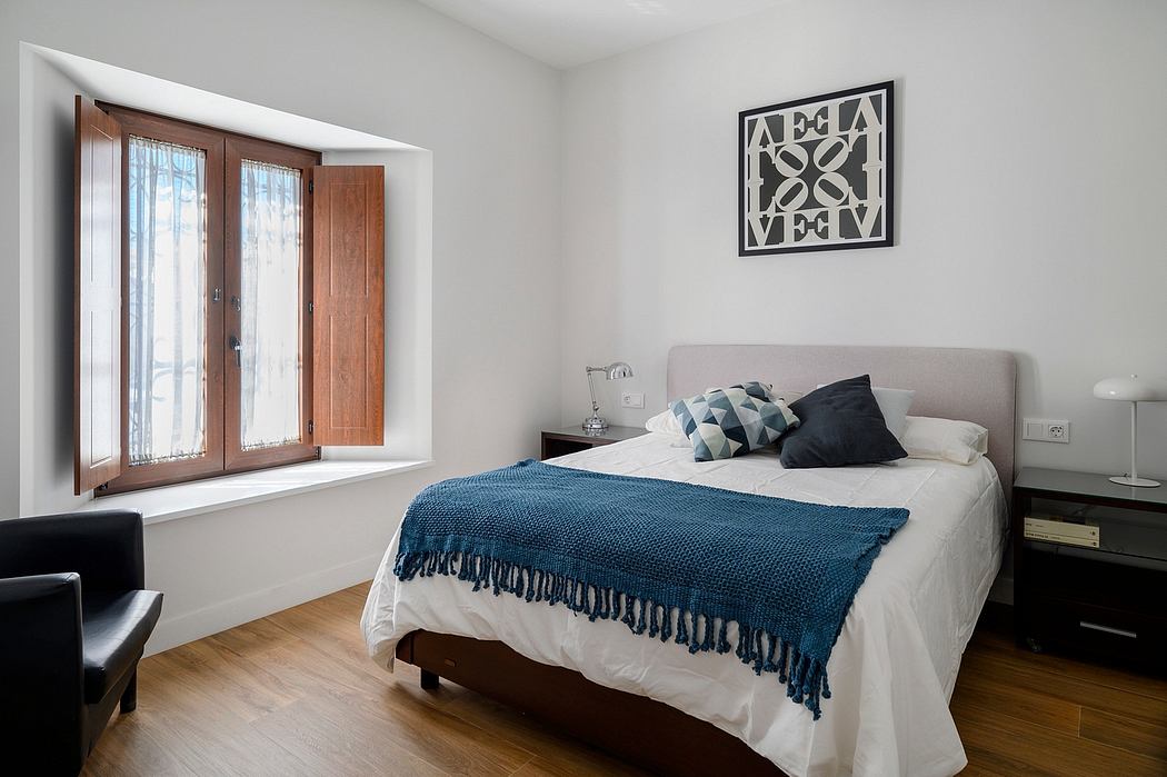Cozy bedroom with wooden accents, modern decor, and large windows overlooking exterior.