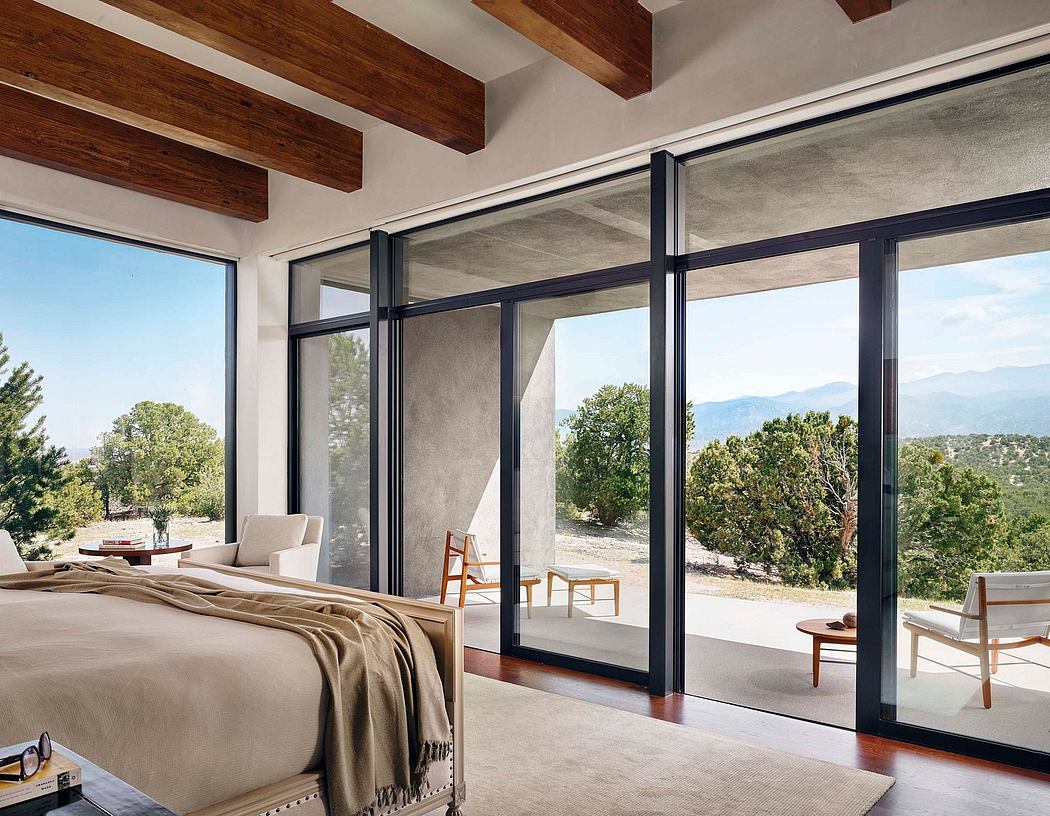 Rustic bedroom with floor-to-ceiling glass walls, wooden beams, and mountain views.