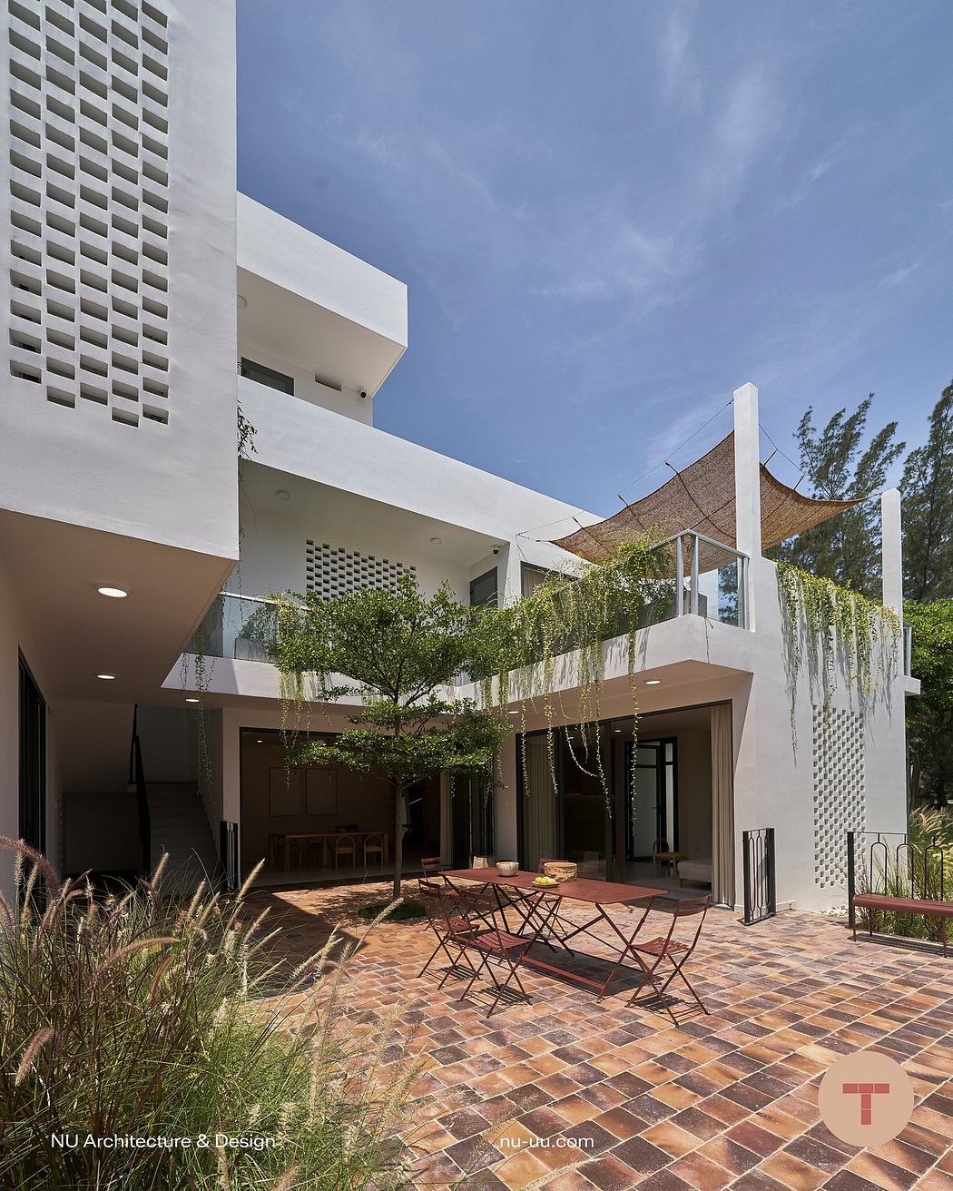 A modern architectural design featuring a courtyard with greenery, brick pavement, and outdoor furniture.