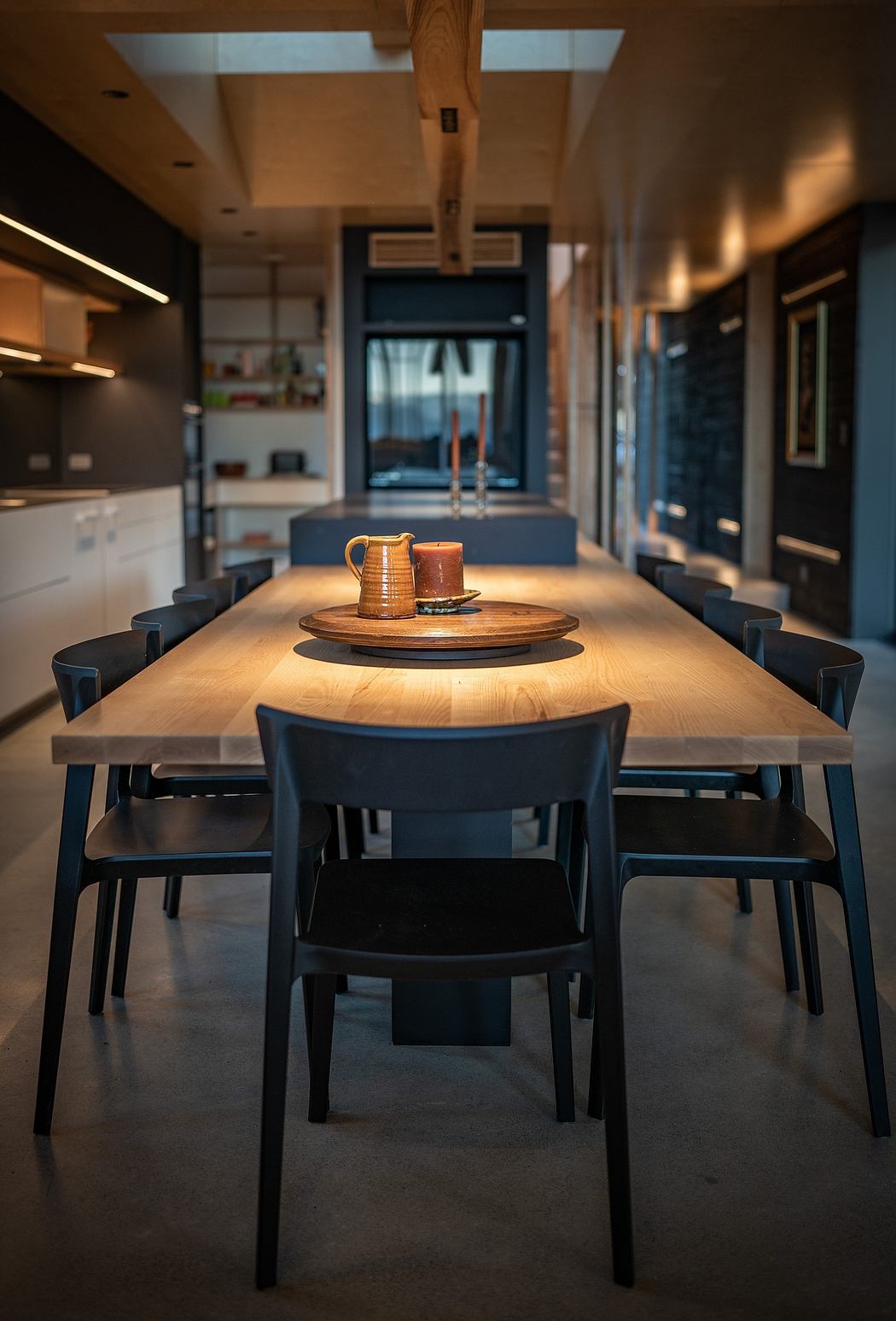 A cozy dining area with a wooden table, black chairs, and warm lighting accents.