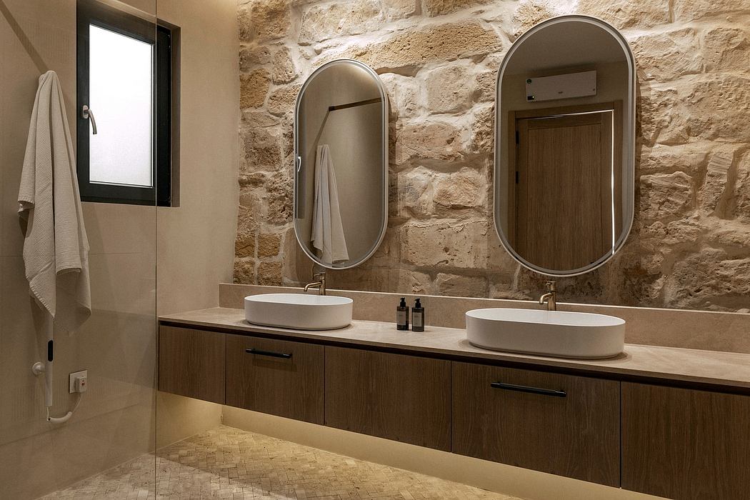 Rustic bathroom with stone walls, wooden vanity, and modern vessel sinks under circular mirrors.