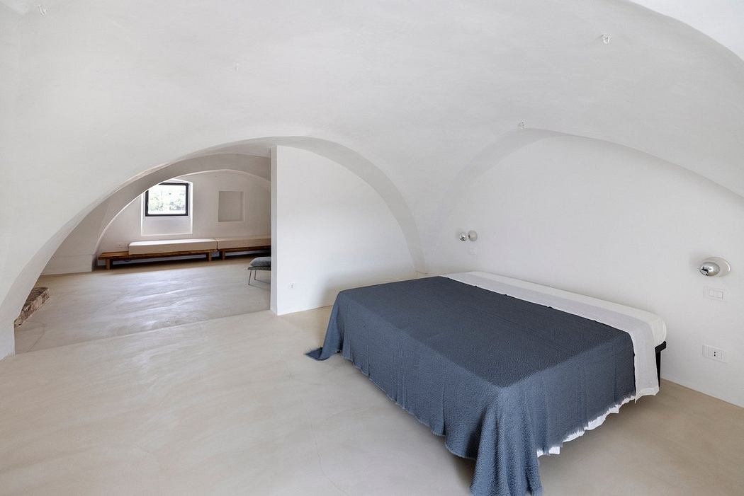 Spacious bedroom with arched entryway, minimalist design, and concrete flooring.