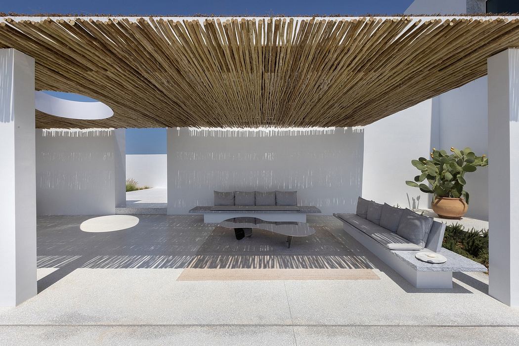 An architectural outdoor seating area with a thatched roof and minimalist concrete design.