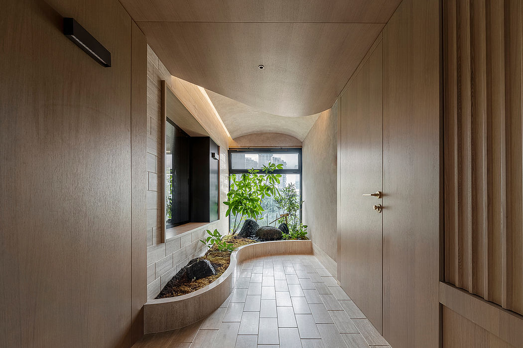 A modern, minimalist hallway with a curved window, plants, and tile flooring.