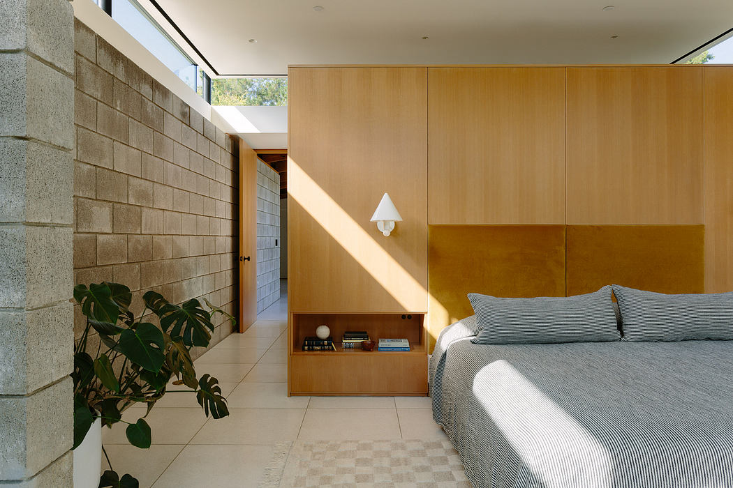 Warm, minimalist bedroom with wooden paneling, built-in shelving, and natural light.