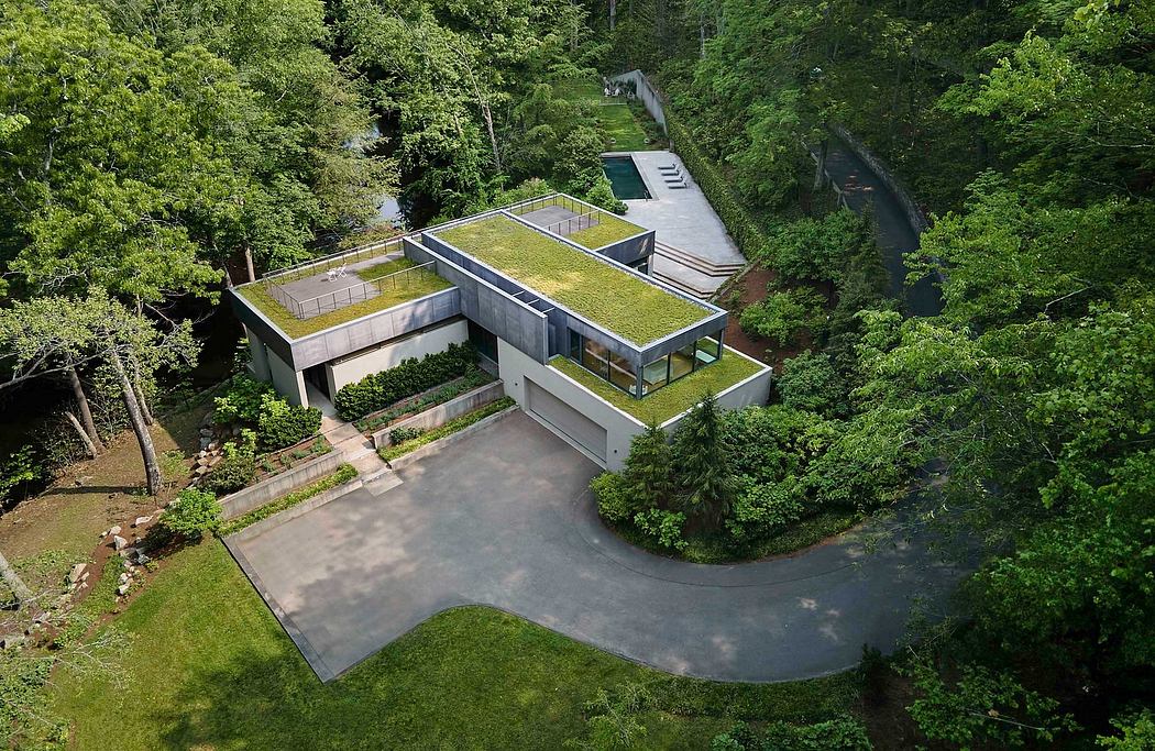 A modern home with a green roof nestled in a lush, forested landscape.