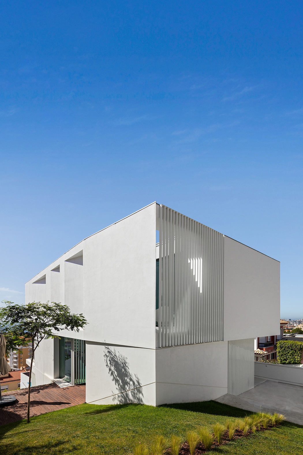 Modern, minimalist building with clean lines, textured facade, and landscaped yard.