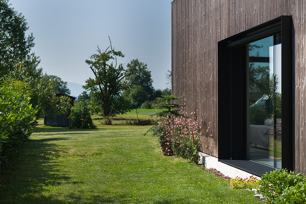 Rustic wooden building with modern geometric black frame windows overlooking lush greenery.