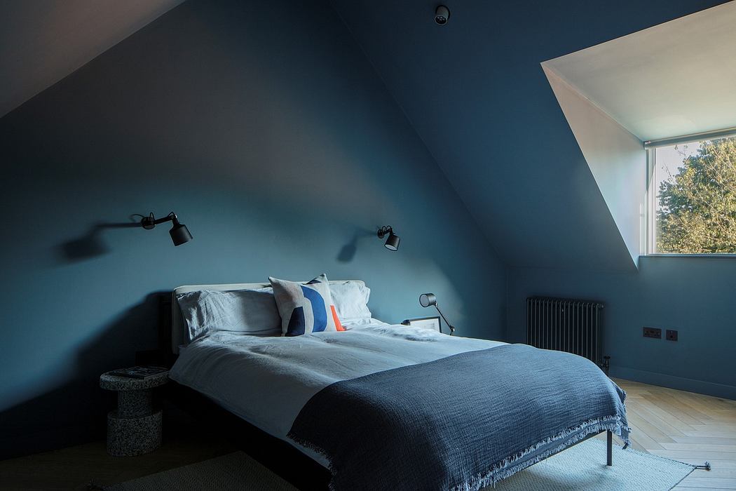 Cozy bedroom with sloped ceiling, moody blue walls, and modern lighting fixtures.