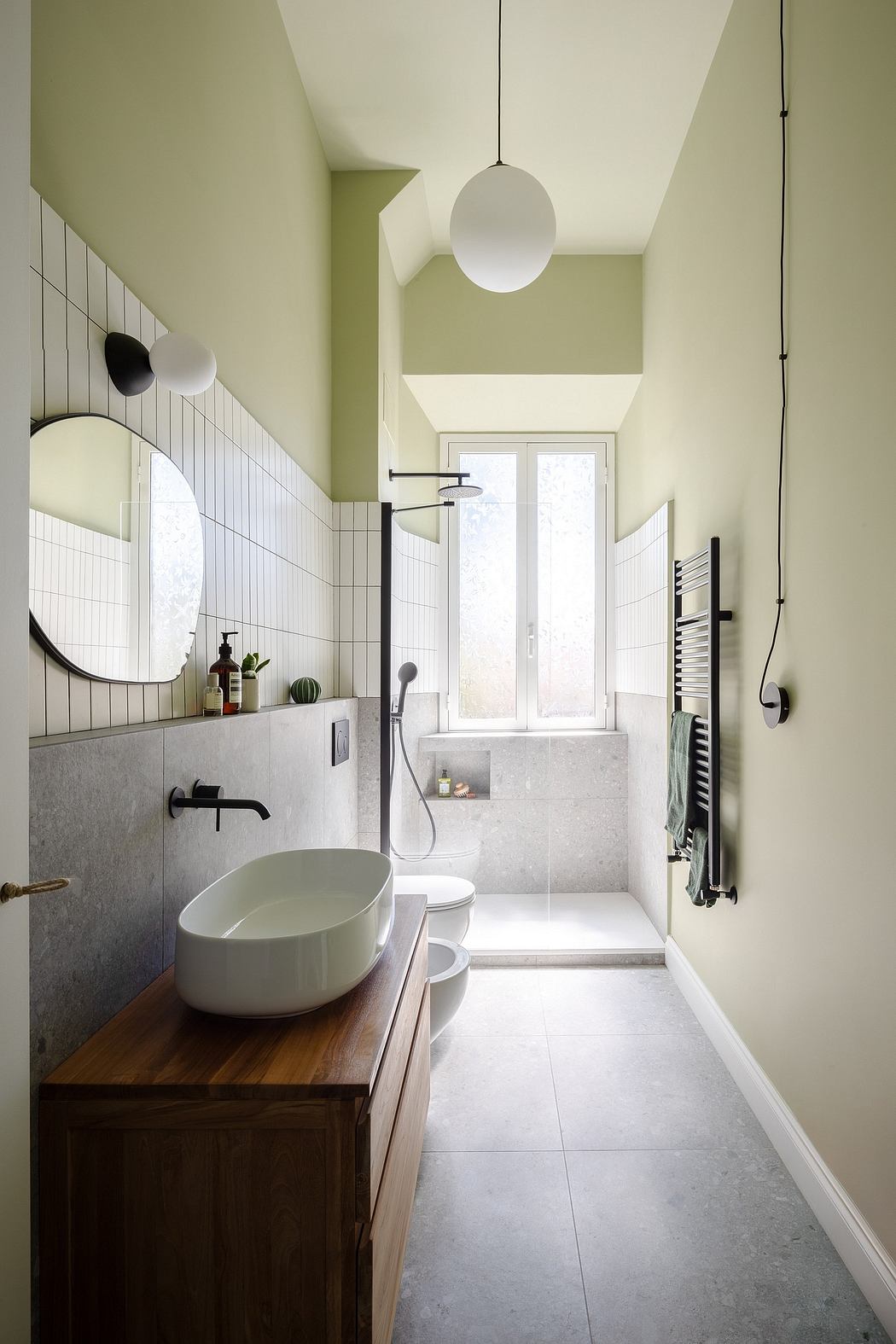 A modern bathroom with sleek tile, a round vanity, and a glass shower enclosure.