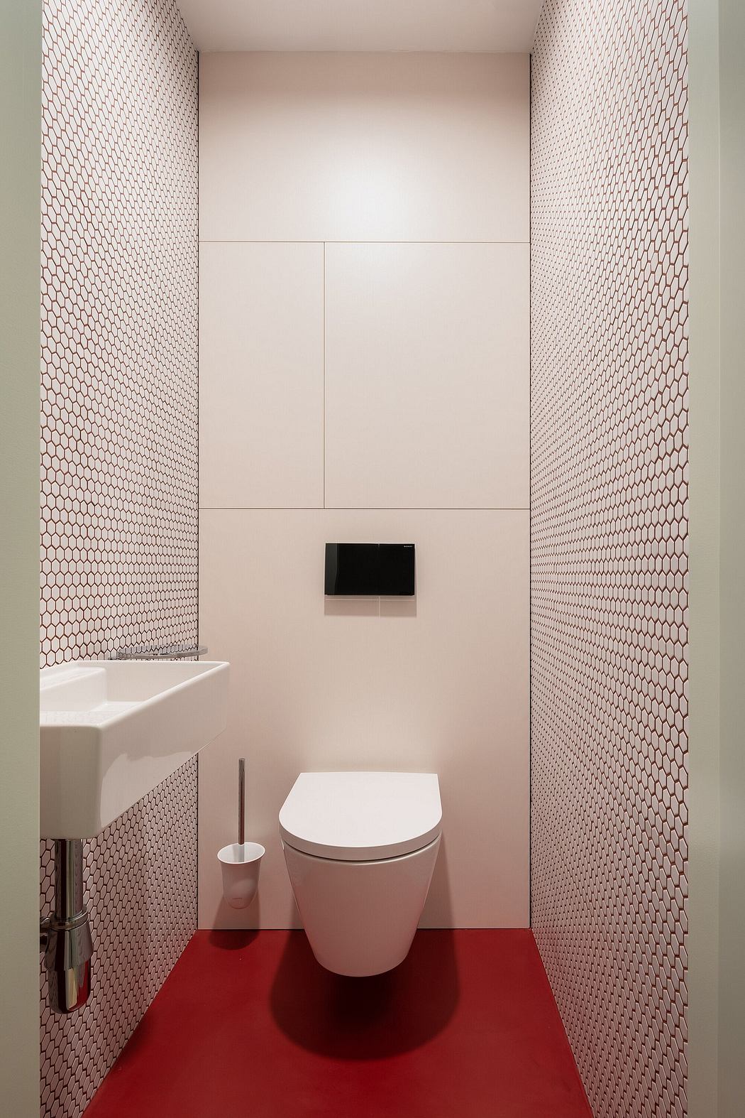 A modern bathroom with a sleek white toilet and patterned pink-and-white tile walls.