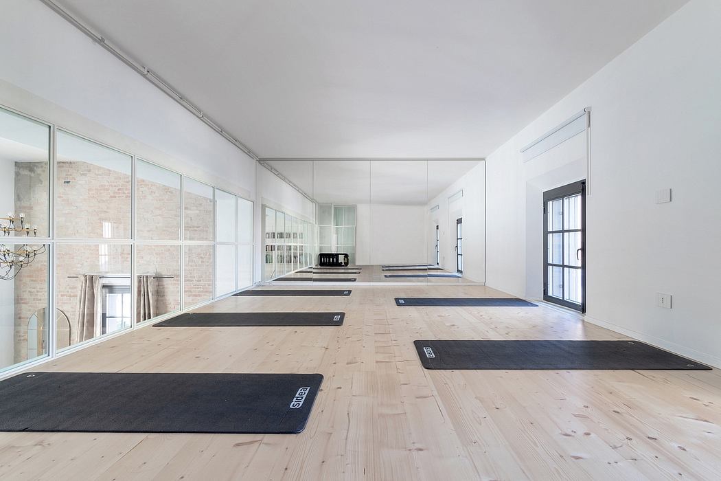 Spacious, modern home gym with hardwood floors, floor-to-ceiling windows, and exercise mats.