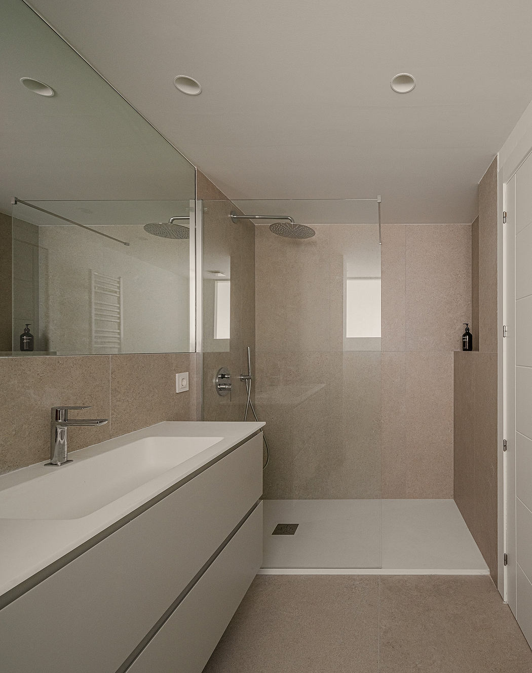 A modern bathroom with minimalist design, featuring a large vanity, shower, and clean lines.