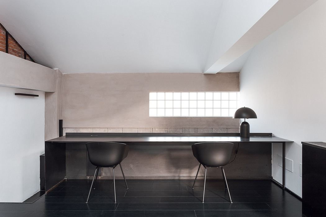 A modern, minimalist kitchen interior with black countertops, chairs, and geometric window patterns.