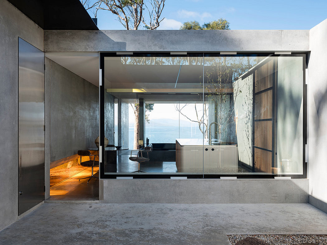 Concrete walls, floor-to-ceiling glass, and minimalist furnishings showcase stunning lake view.