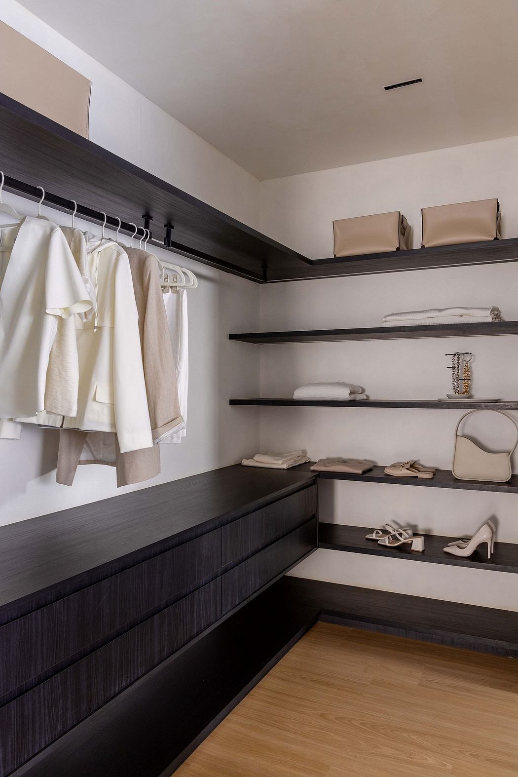 Well-organized bedroom closet with dark wood shelves, hanging rods, and neatly stored items.