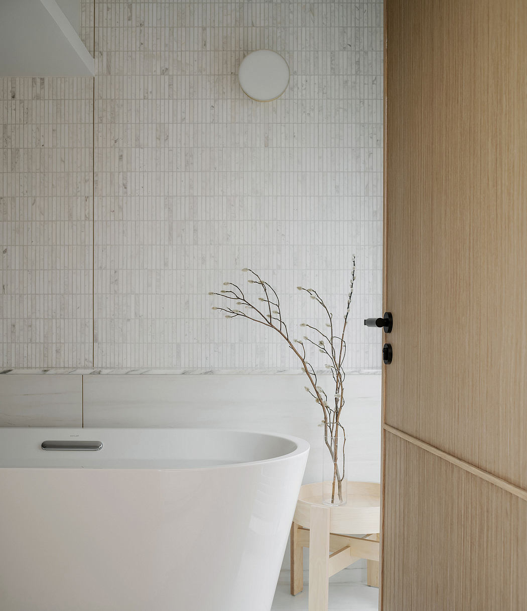 Minimalist bathroom with a modern tub, intricate tile pattern, and a decorative branch.
