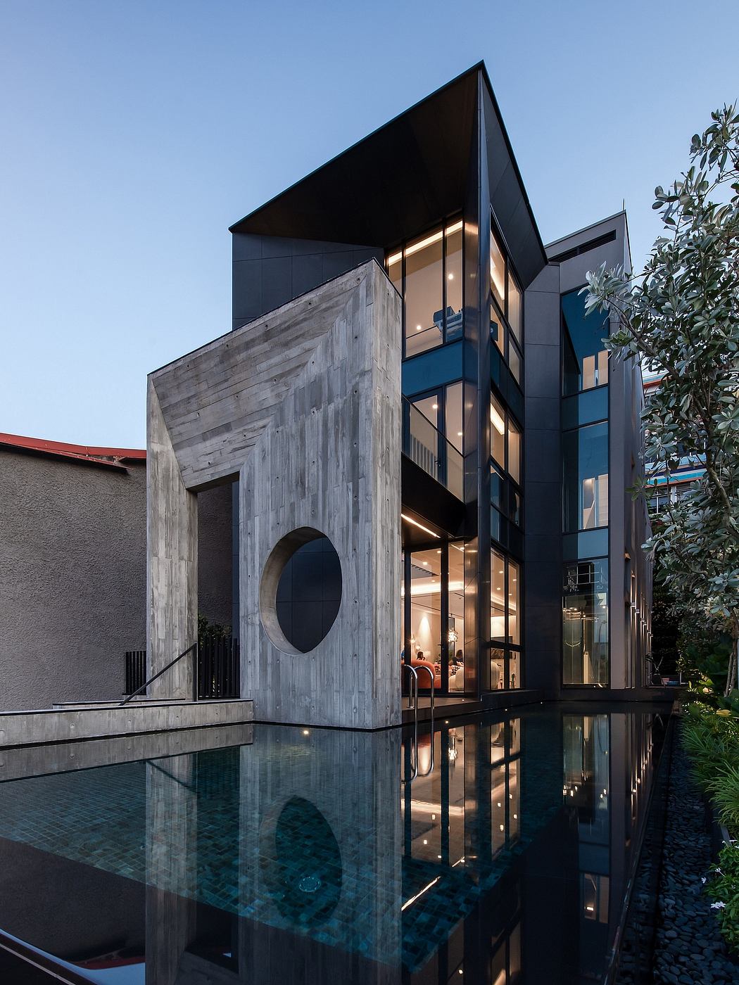 Modern architectural design with geometric shapes, glass walls, and reflective pool.