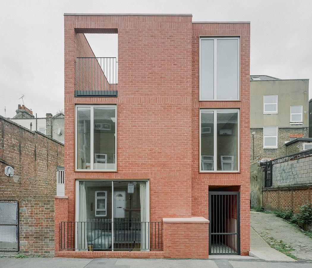 A modern, multi-story brick building with large windows and a balcony.