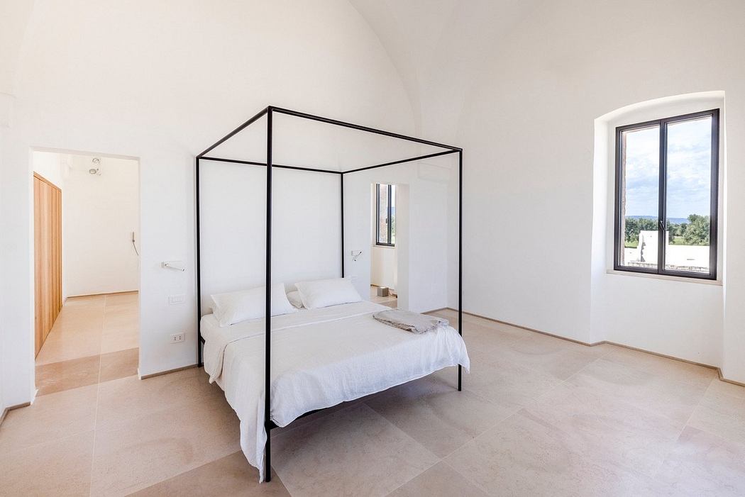 Modern minimalist bedroom with sleek black metal canopy bed frame and large window.
