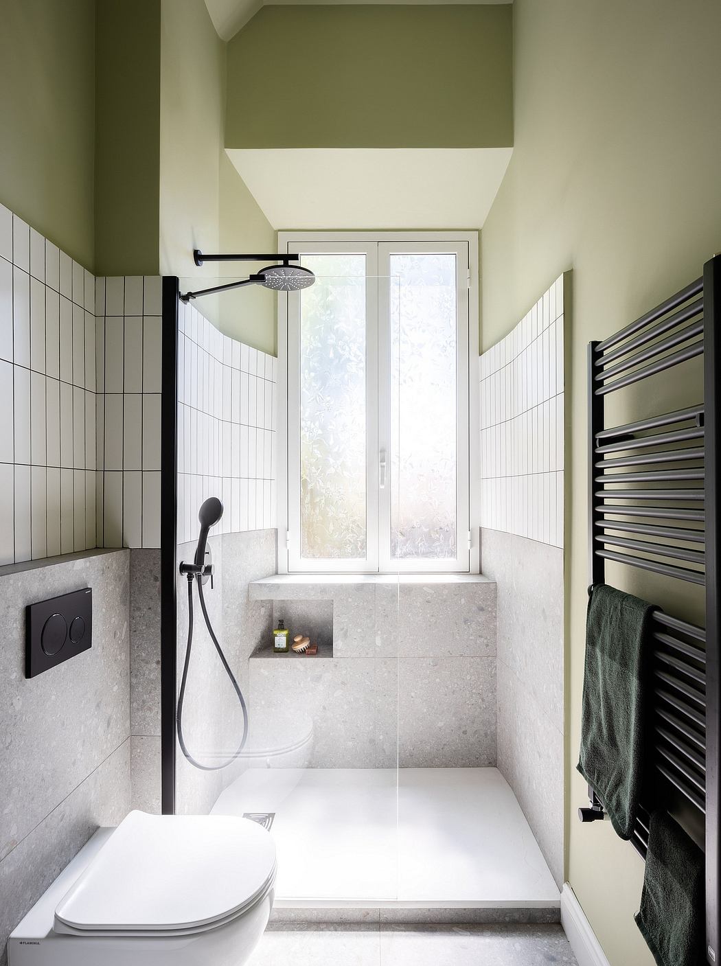 Minimalist bathroom with tiled walls, built-in shower, and window providing natural light.