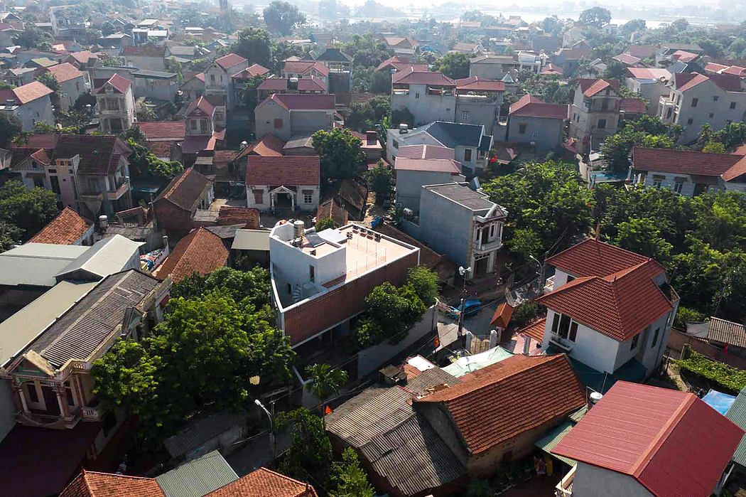 Densely packed buildings with red tiled roofs and lush greenery in the foreground.