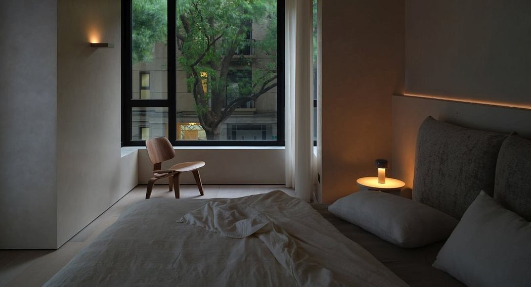 Cozy bedroom with large windows overlooking a tree-lined street, minimalist furniture.