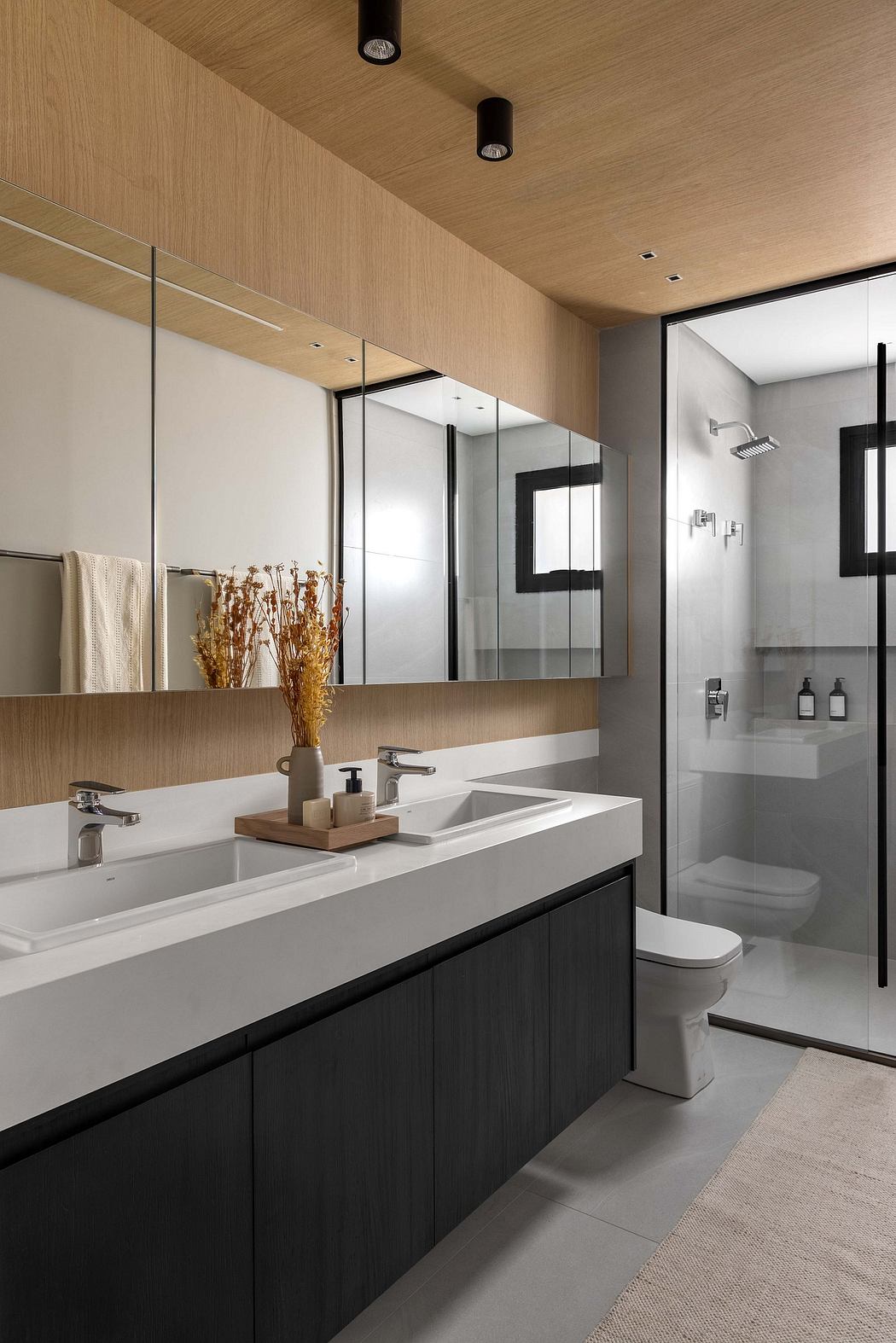 Sleek modern bathroom with a double vanity, tiled shower, and textured wood walls.