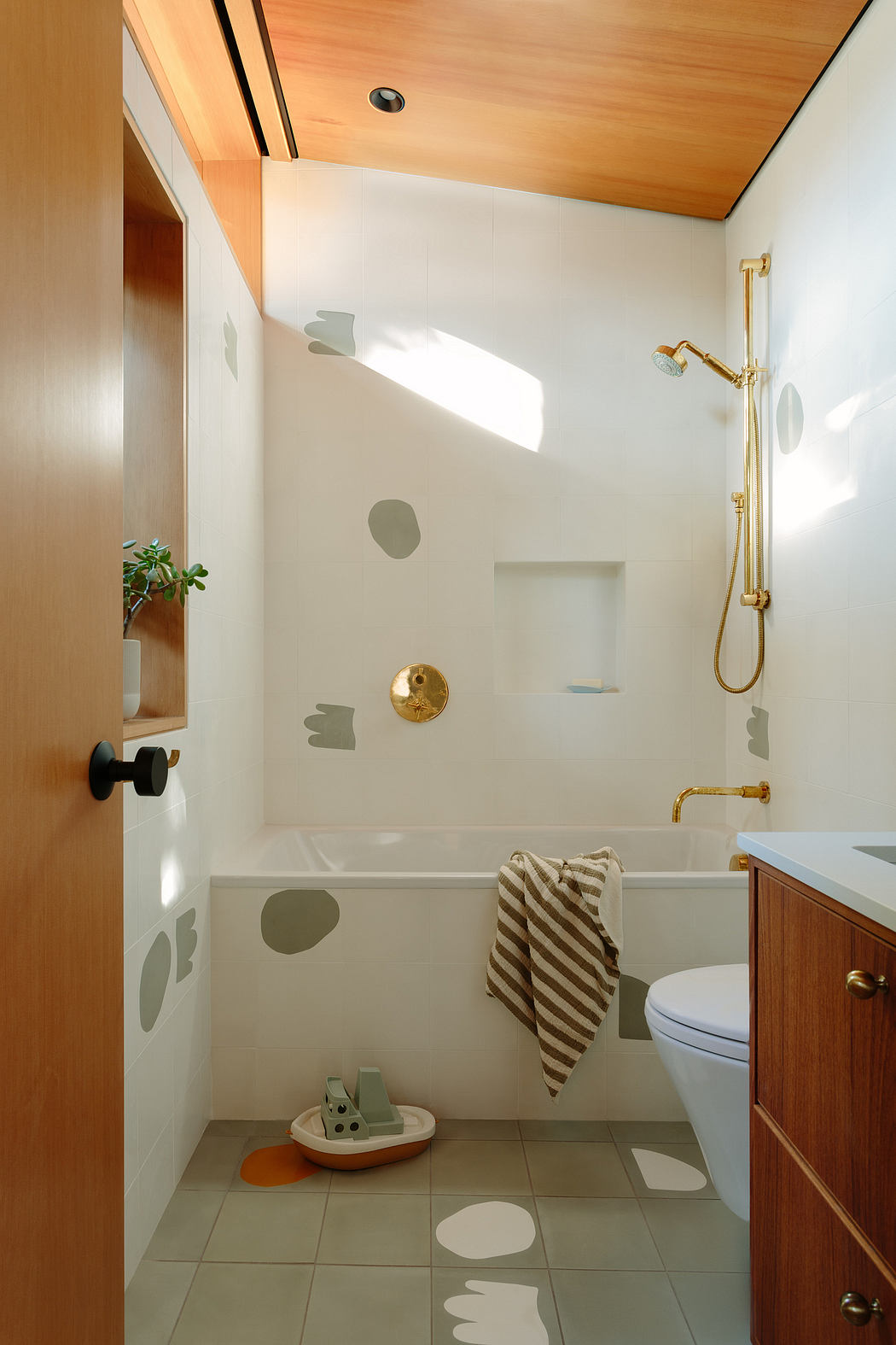 Warm-toned wood ceiling, white walls, and gold-toned fixtures create a modern, spa-like bathroom.